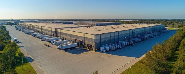 Aerial view of large industrial warehouse complex with parked trucks Warehousing